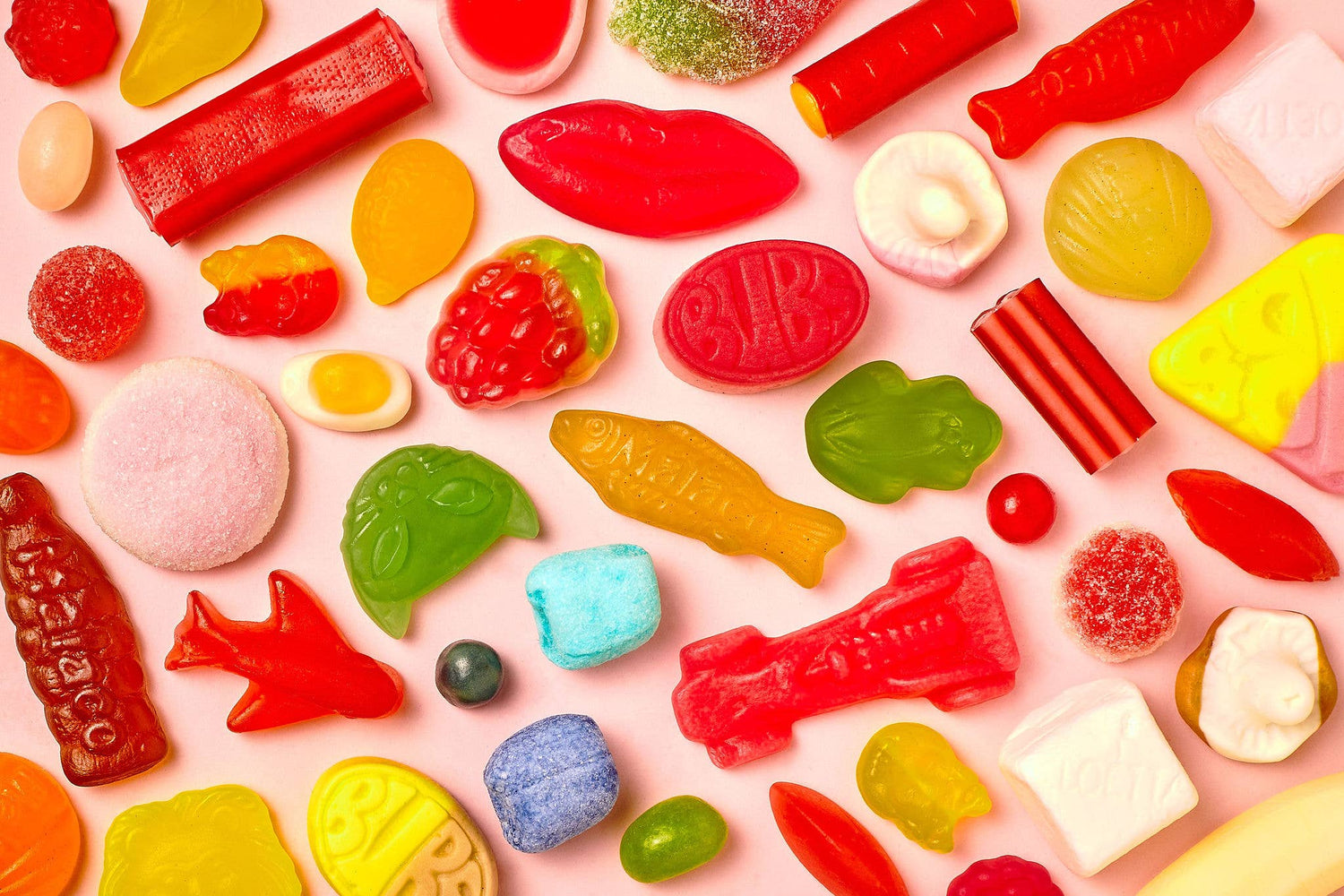 Assorted colorful Swedish gummy candies on a pink background